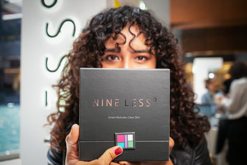 Invitada de cabello rizado mostrando una caja de producto