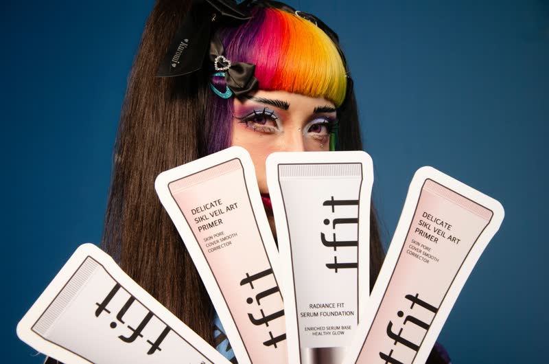 Creadora con cabello multicolor mostrando tarjetas de producto