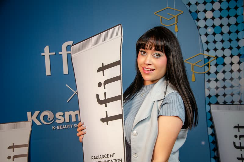 Creadora con el display gigante del producto frente al muro de tfit por Kosmetics