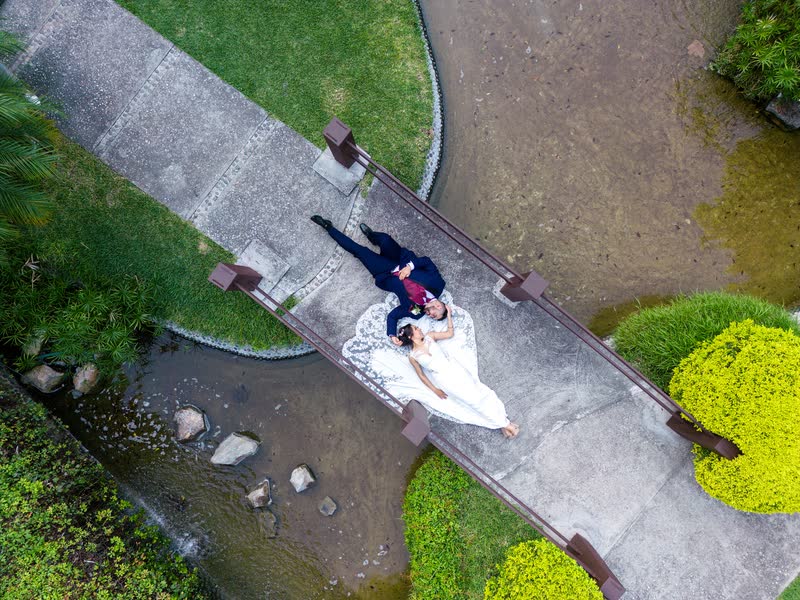 Toma cenital con drone de una pareja de novios sobre un puente de madera