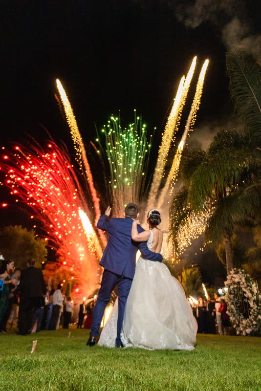 Pareja de espaldas frente a fuegos artificiales de colores