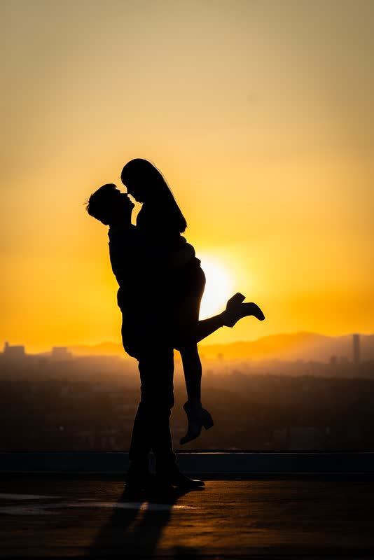 Silueta de una pareja abrazada contra el atardecer naranja de la ciudad