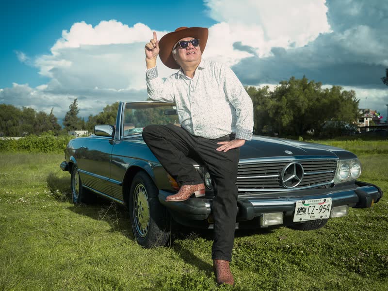 Hombre con sombrero vaquero posando sobre un Mercedes clásico