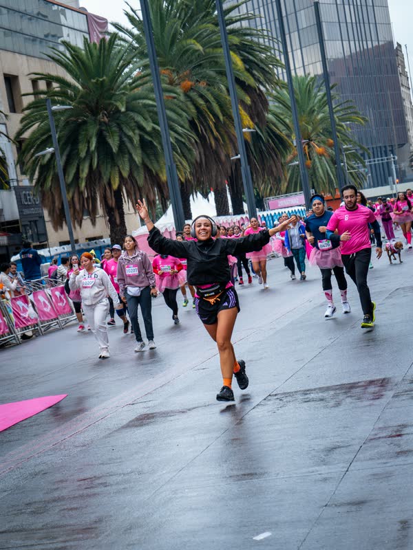 Corredora celebrando con los brazos abiertos en una carrera por Reforma